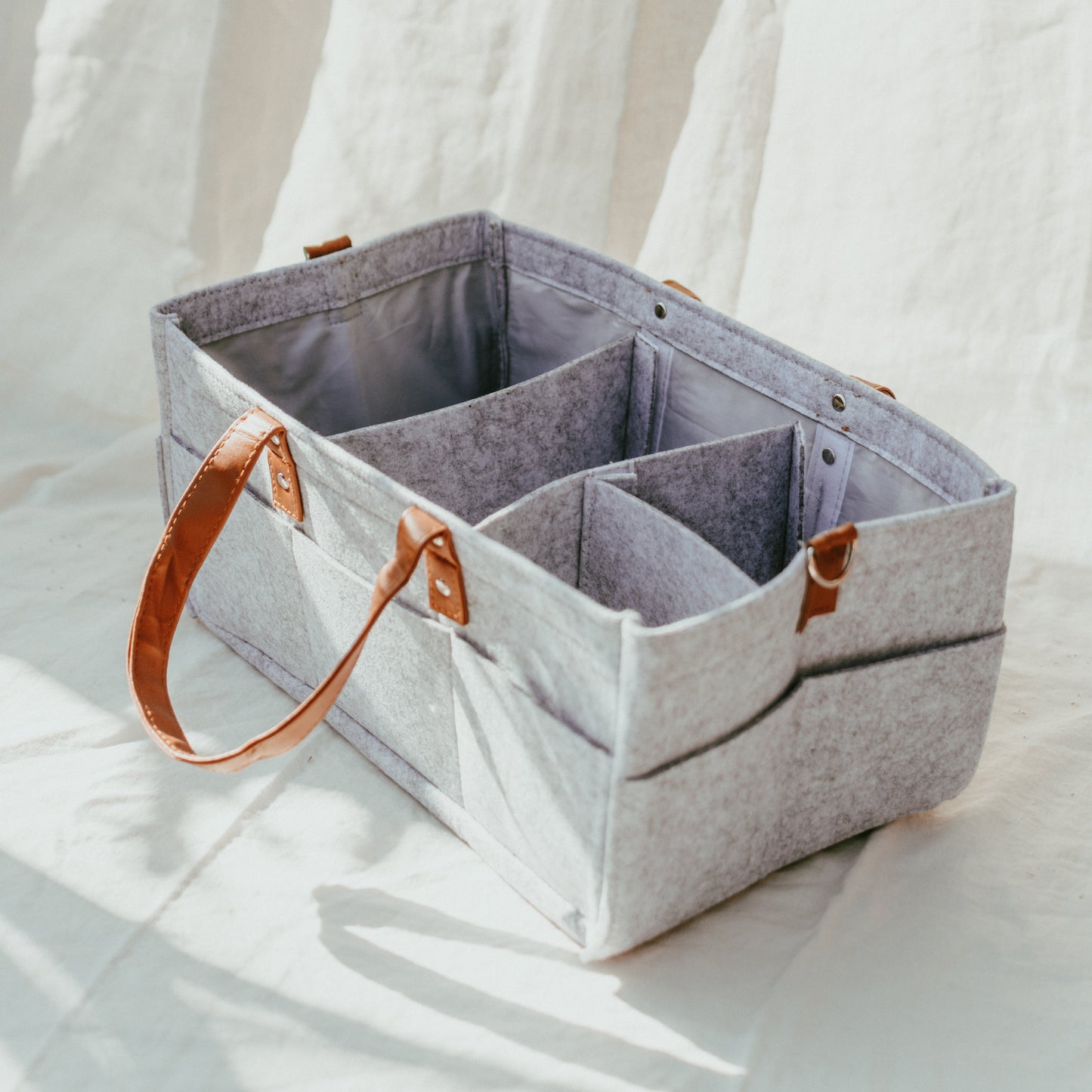 Gray fabric storage caddy with brown leather handles on a white background